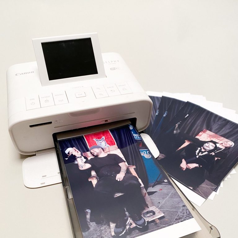 Drucker mit Fotoausgaben und einem Bildschirm, der Bilder anzeigt.