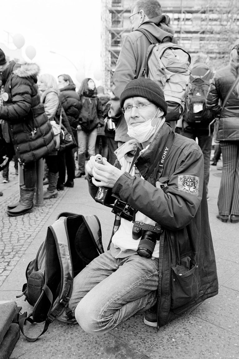 Ein Fotograf kniet auf dem Boden und hält eine Kamera, um sein Film neu zu laden.